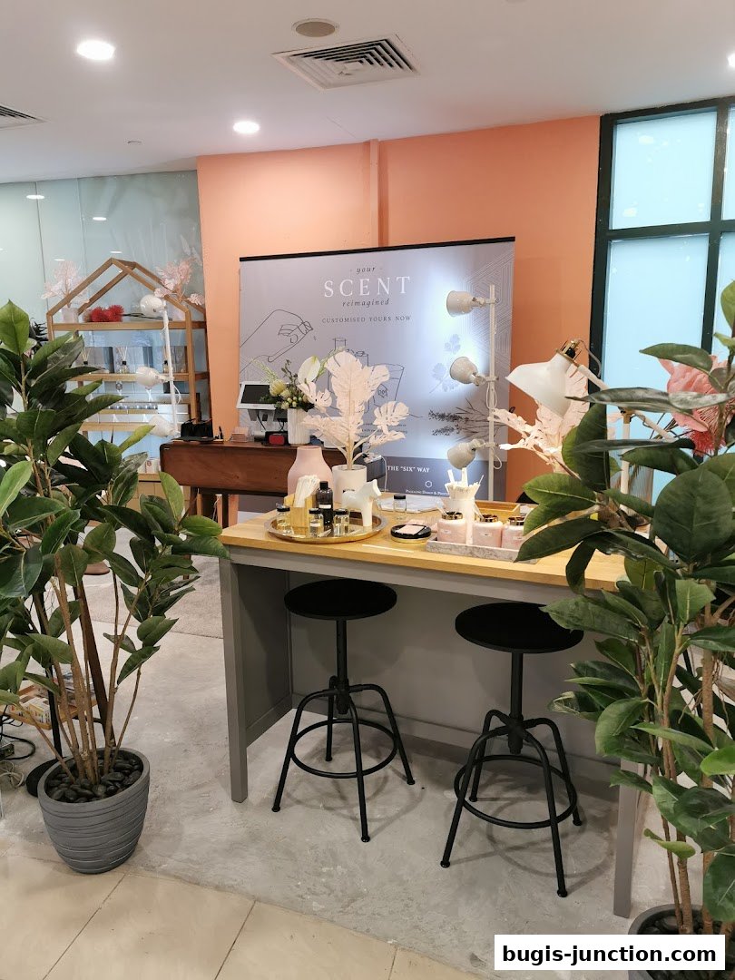 A display counter with perfume bottles and stools, surrounded by plants.