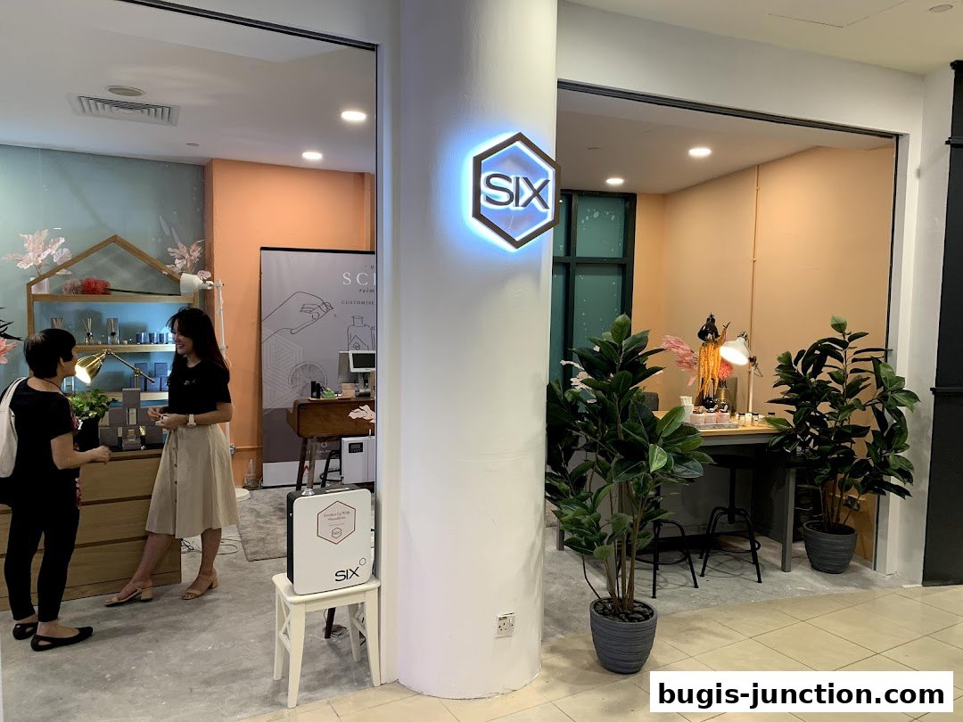 Two women are browsing in a well-lit shop with a prominent 'SIX' logo and decorative plants.