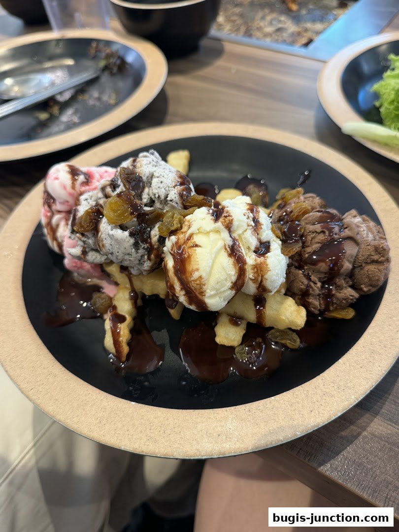 A plate of ice cream with chocolate sauce and raisins, served with fries.
