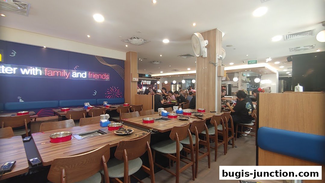 Interior of a busy Korean BBQ restaurant with diners and tables set for a meal.