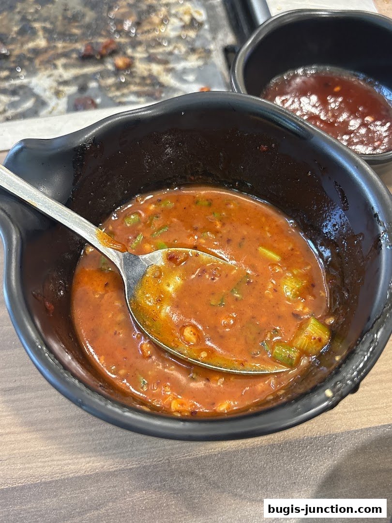 A close-up of a bowl of dipping sauce with a spoon, with another bowl of sauce in the background.