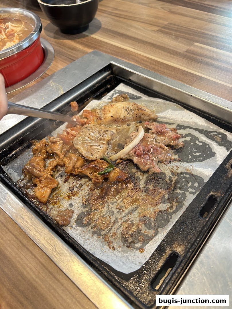 A close-up of various meats being grilled on a hot plate at Seoul Garden.