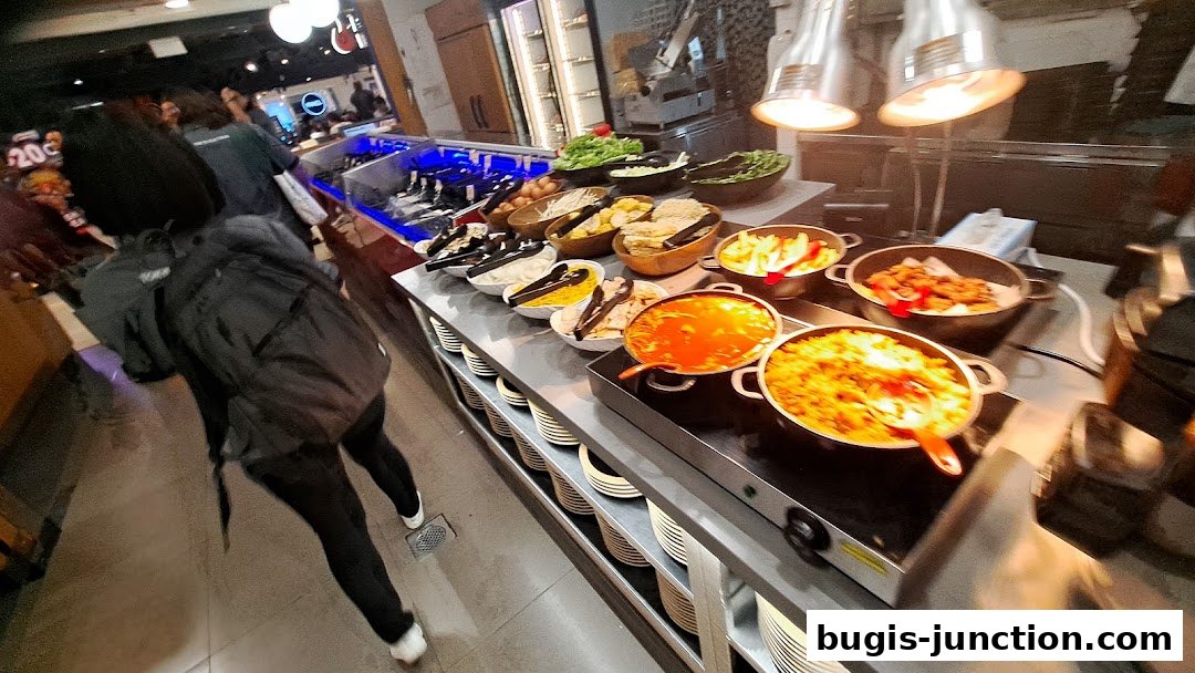 A buffet spread with various dishes and fresh ingredients, with customers selecting food.