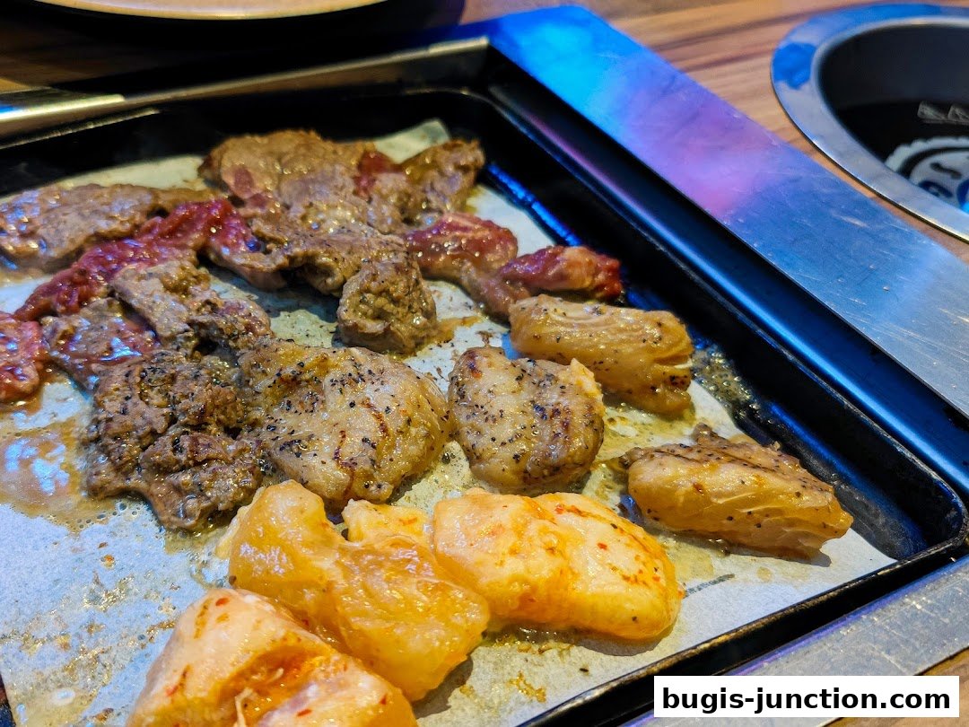 Close-up of various grilled meats and seafood sizzling on a hot plate.