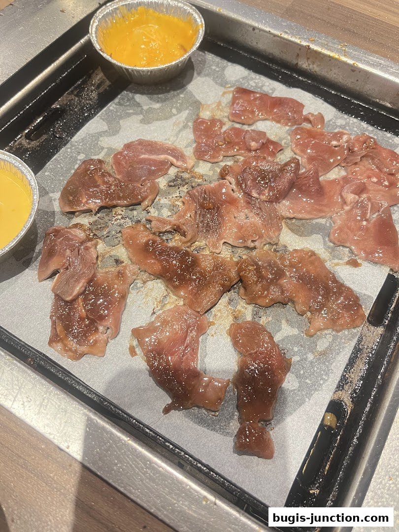 Thinly sliced raw meat and dipping sauce on a grill.