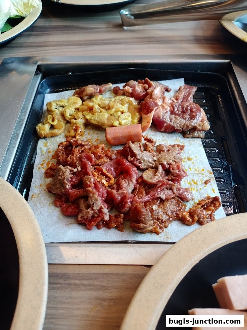 A close-up shot of raw marinated meats and a sausage on a grill.
