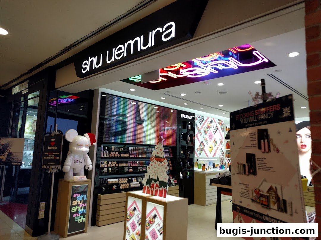 The entrance of a Shu Uemura cosmetics store with colorful displays and promotional signage.