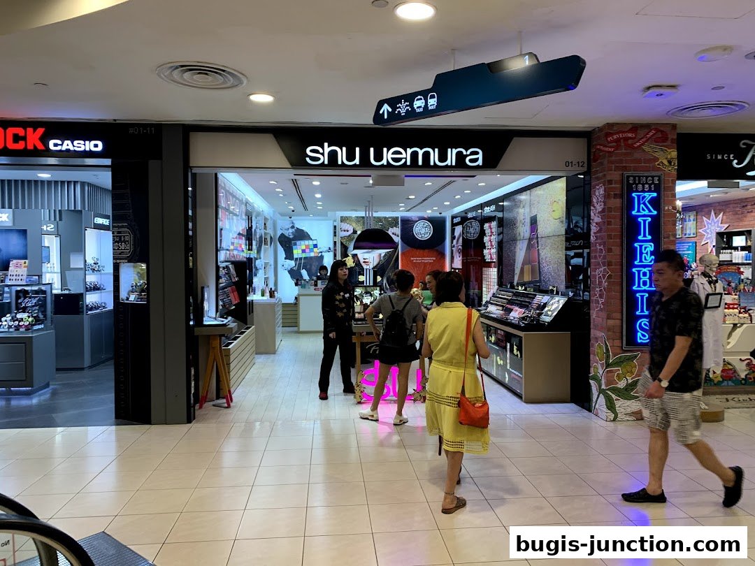 The shu uemura shop front with customers browsing makeup displays.