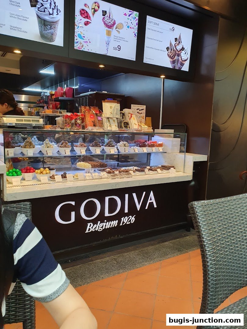 A Godiva chocolate shop counter displaying various chocolates and soft-serve ice cream.
