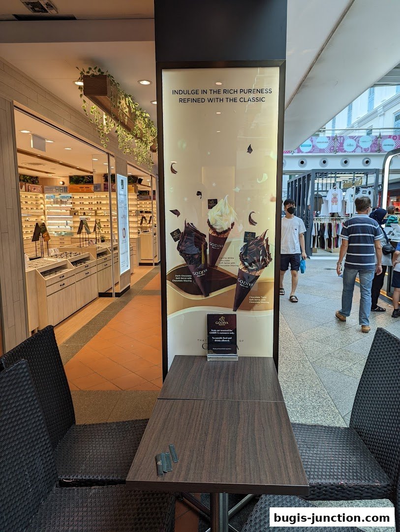A Godiva shop display featuring ice cream cones and seating area.
