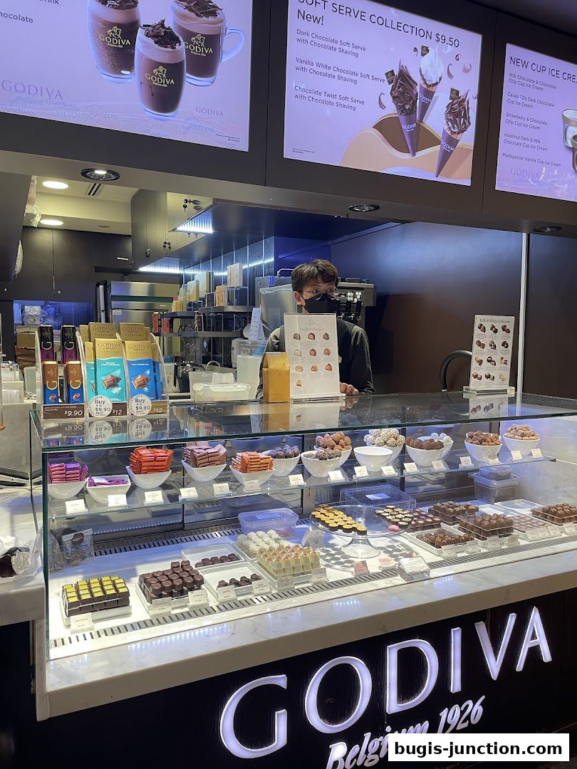 A Godiva chocolate shop counter displaying various chocolates and soft serve ice cream.