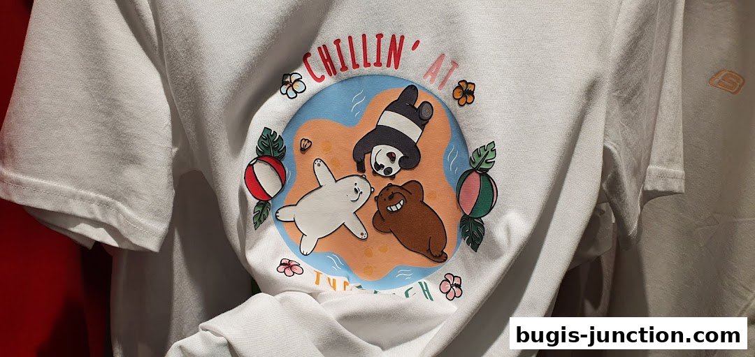 A white t-shirt with a graphic print of cartoon bears chilling on a beach.