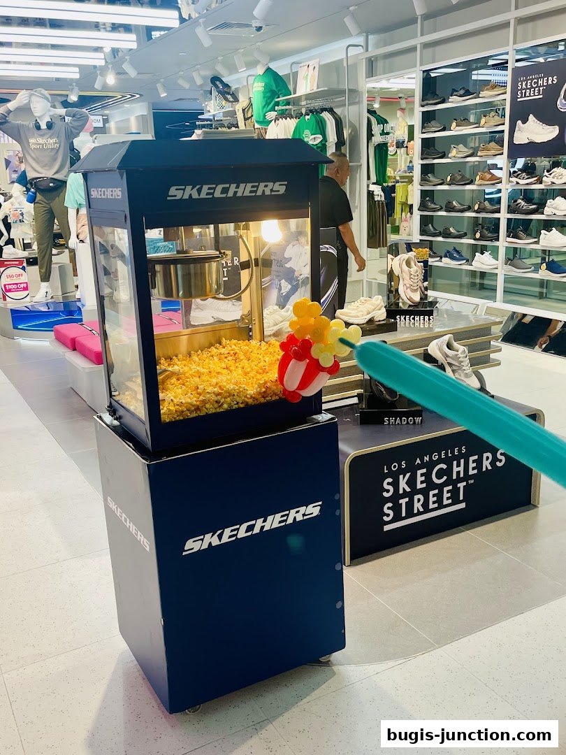 A Skechers store interior with a popcorn machine and displays of shoes and apparel.