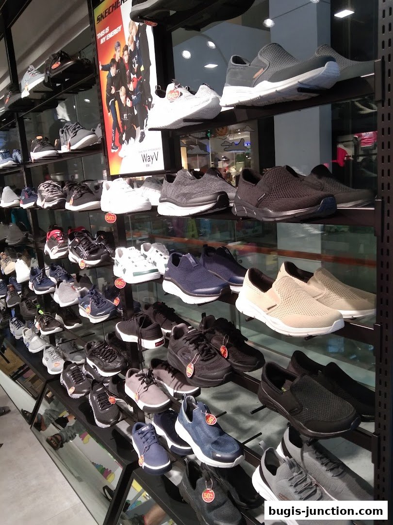 A wide selection of Skechers shoes displayed on shelves in a retail store.