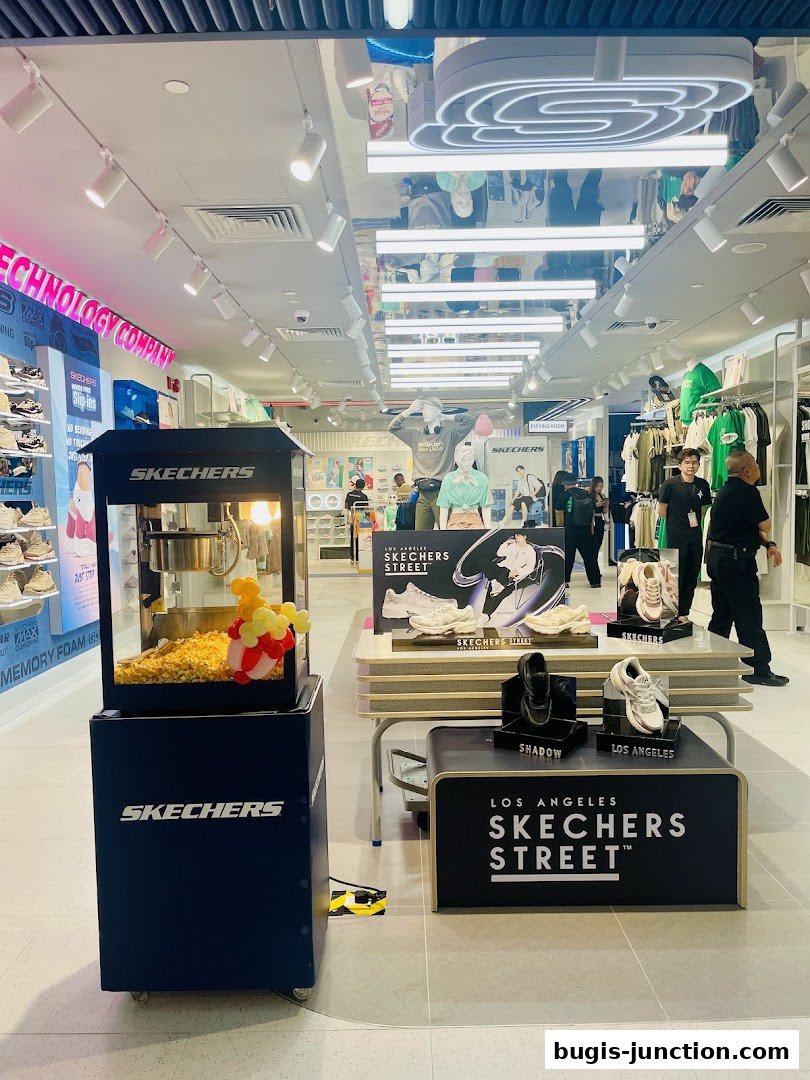 Interior view of a Skechers store with shoes displayed and a popcorn machine.