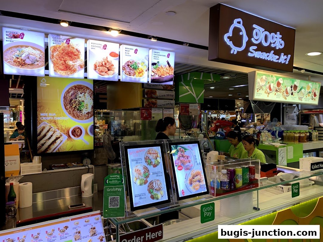 A food stall with illuminated menu boards displaying various dishes and a prominent brand sign.