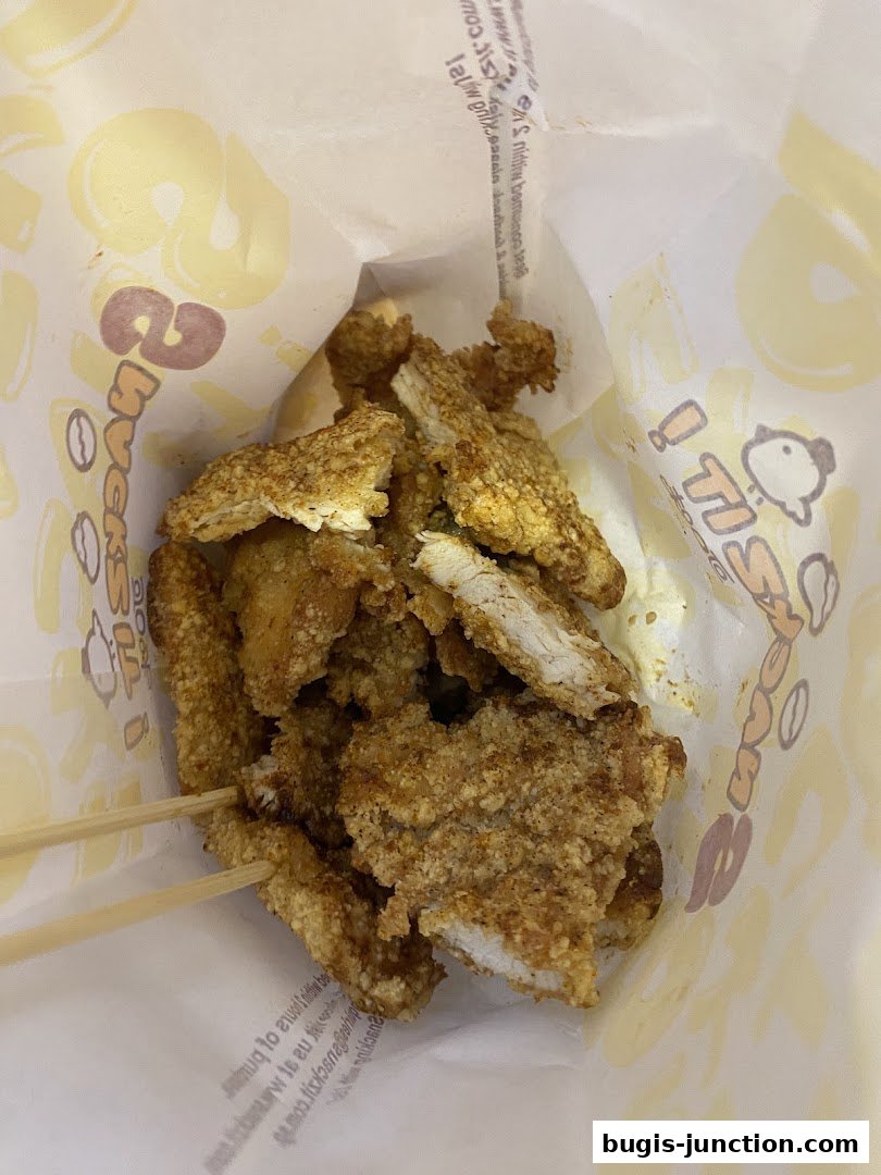 A bag filled with crispy fried chicken pieces on wooden skewers.