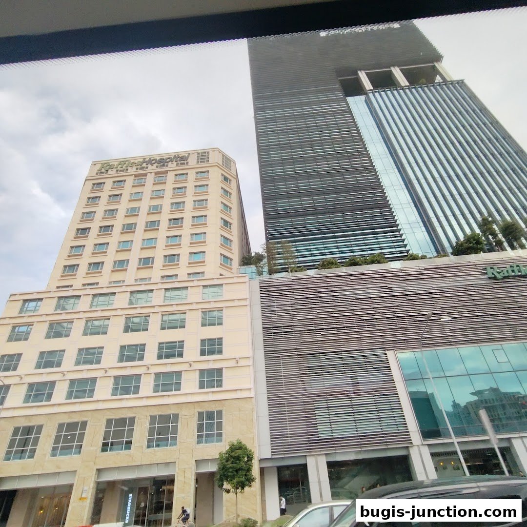 Modern skyscrapers, one with a beige facade and the other with a dark, ribbed exterior.