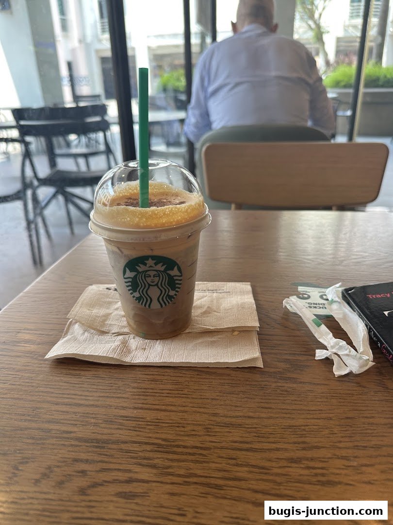 A Starbucks iced coffee drink sits on a napkin on a wooden table.