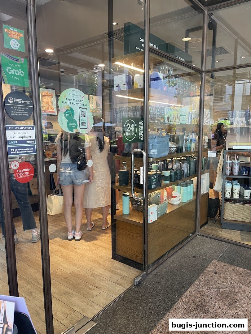 The entrance to a Starbucks store with merchandise displayed on shelves and customers inside.