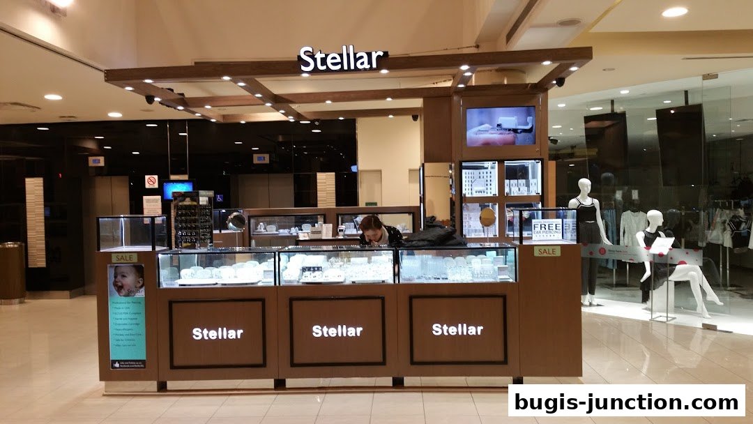 A Stellar jewelry kiosk displays earrings and jewelry, with mannequins in the background.