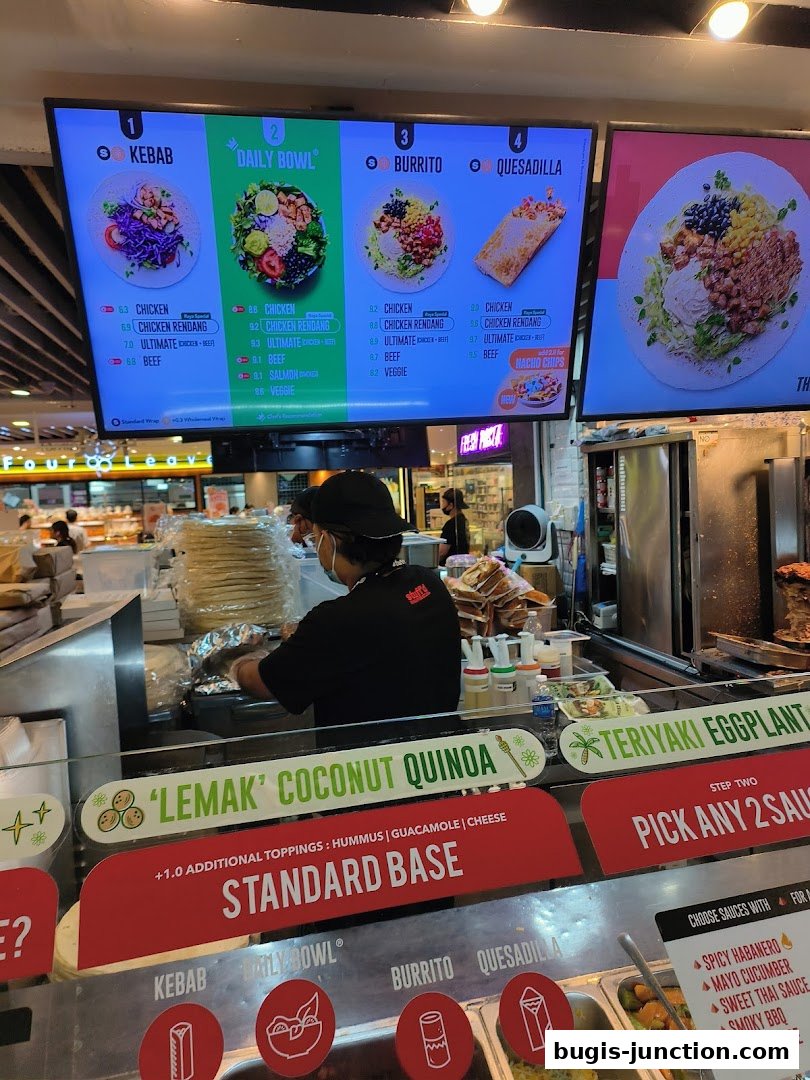 A digital menu board displays various meal options like Kebab, Daily Bowl, Burrito, and Quesadilla with prices.