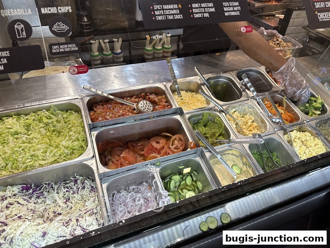A display of fresh ingredients for build-your-own meals, including lettuce, tomatoes, and various toppings.