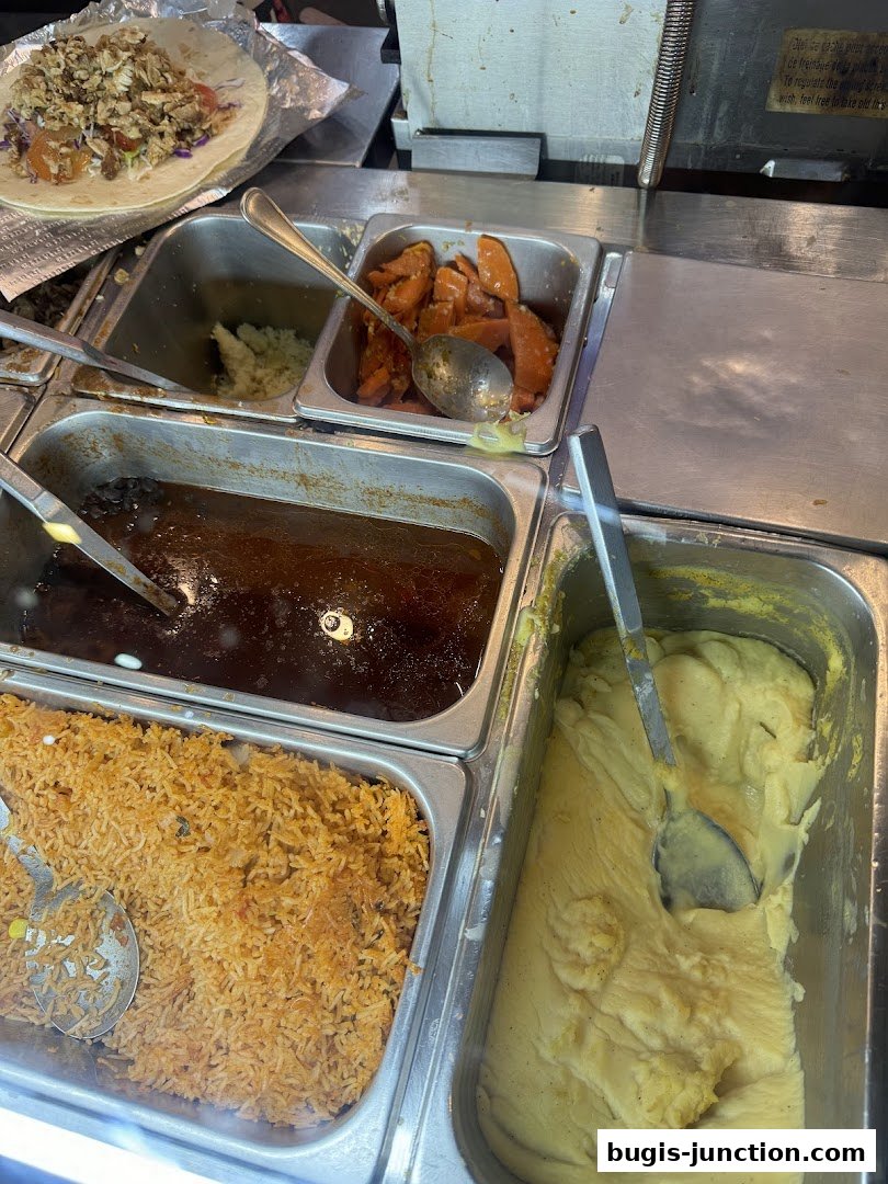 A close-up of a food counter with various ingredients for burritos and sides.