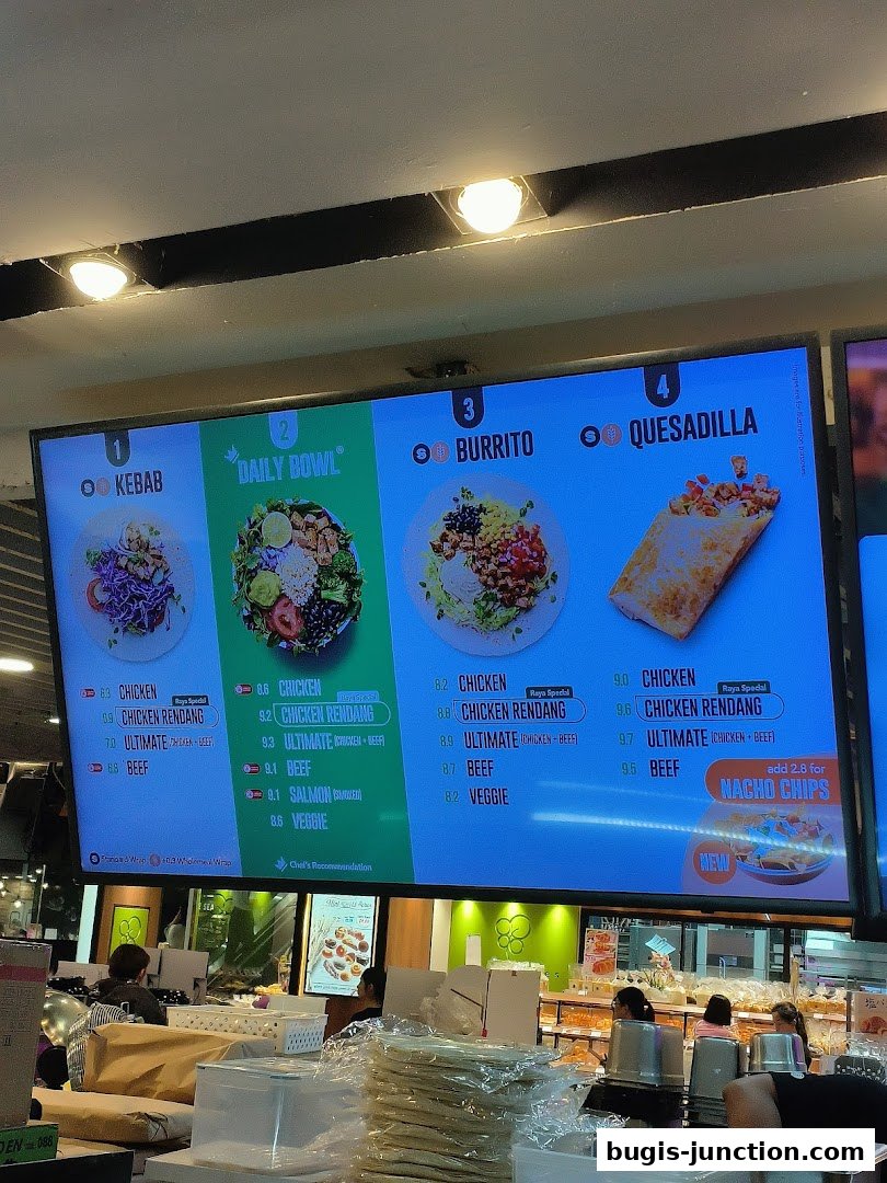A digital menu board displaying various food options like kebabs, bowls, burritos, and quesadillas.