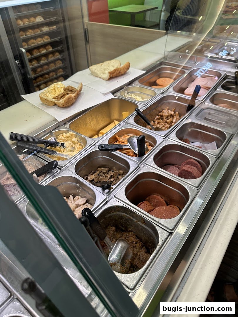A Subway sandwich bar with various fillings and bread options displayed.