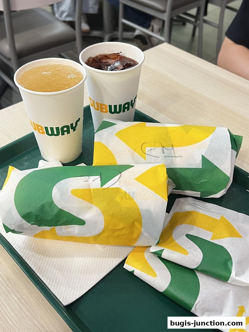 Two Subway sandwiches and drinks on a tray with napkins.