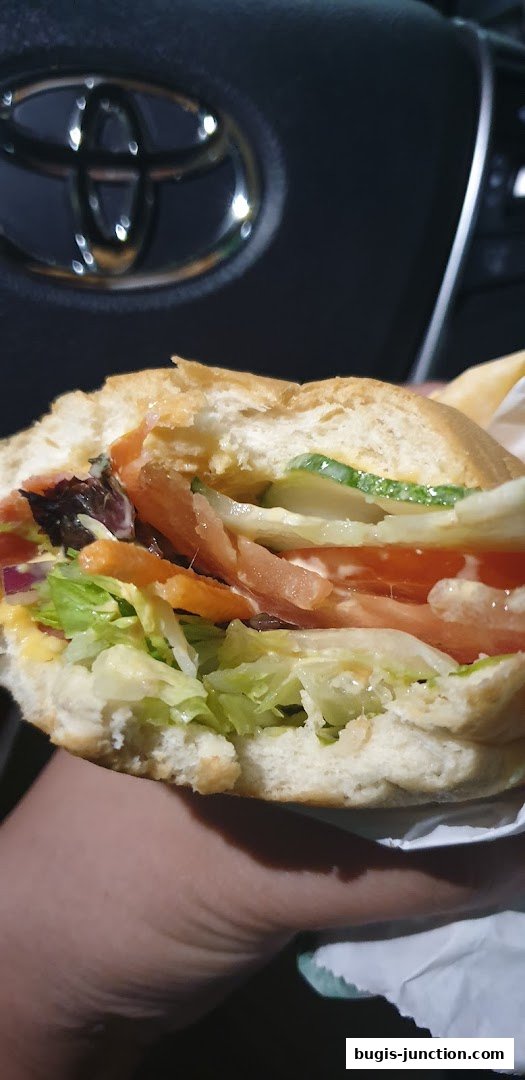 A close-up shot of a Subway sandwich with fresh lettuce, tomatoes, cucumbers, and meat.