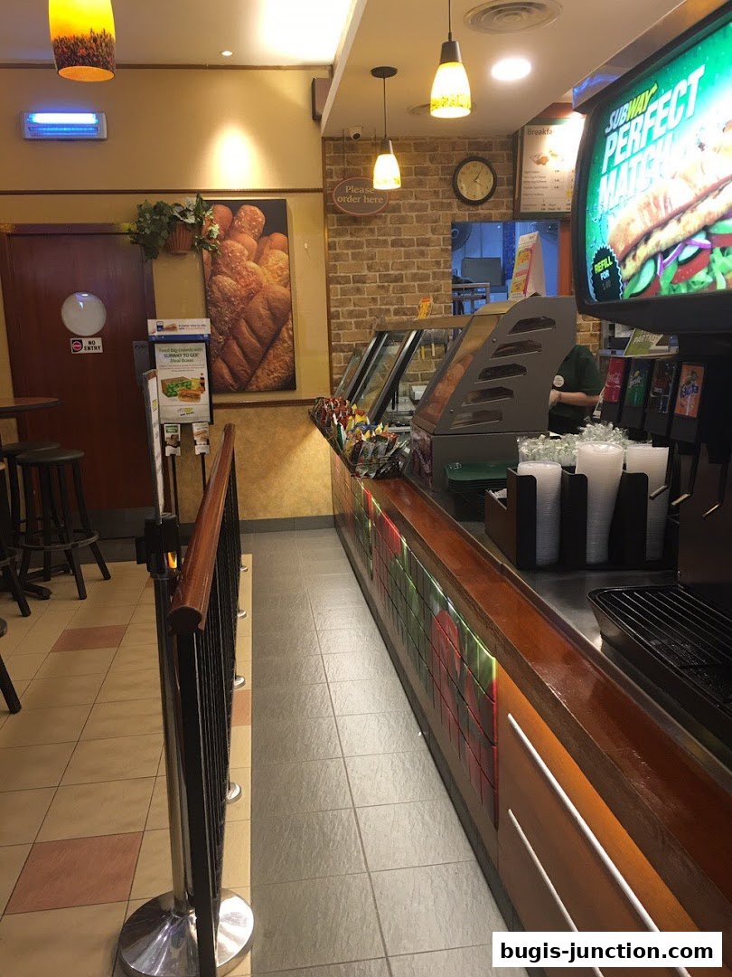 Interior view of a Subway restaurant showing the counter, display cases, and seating area.