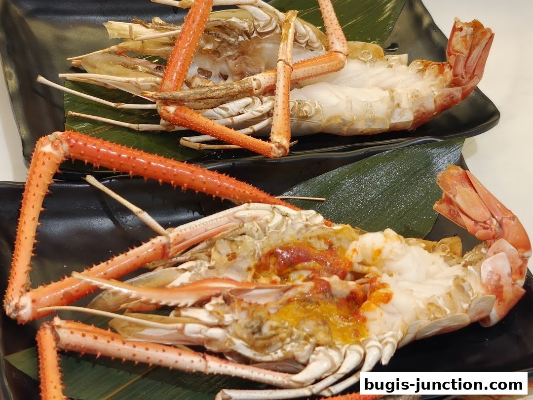 Two plates of cooked prawns, garnished with sauce and served on banana leaves.