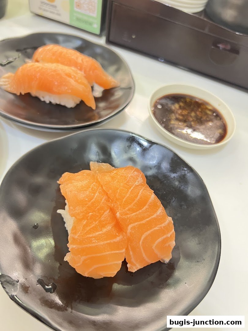 Close-up of fresh salmon sushi on black plates with soy sauce.