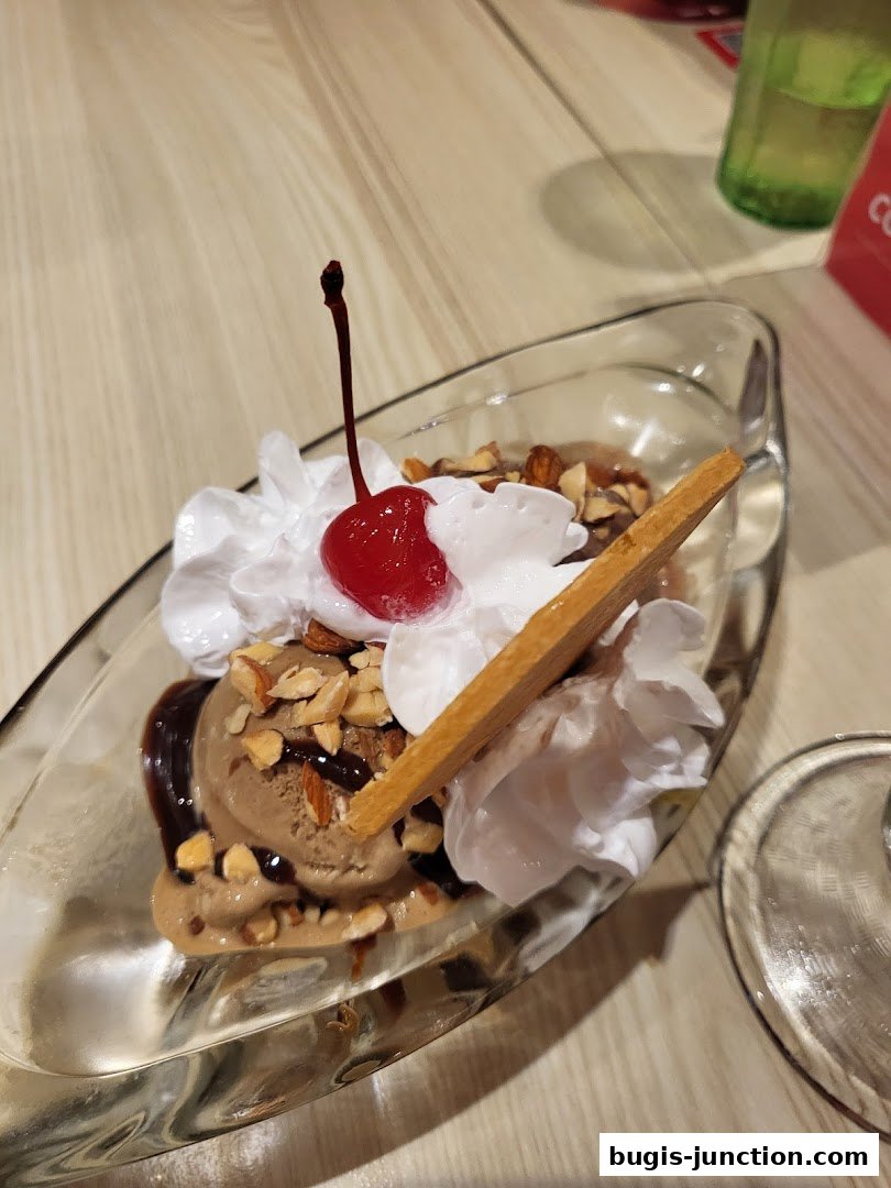 A delicious ice cream sundae with chocolate ice cream, whipped cream, nuts, and a cherry.