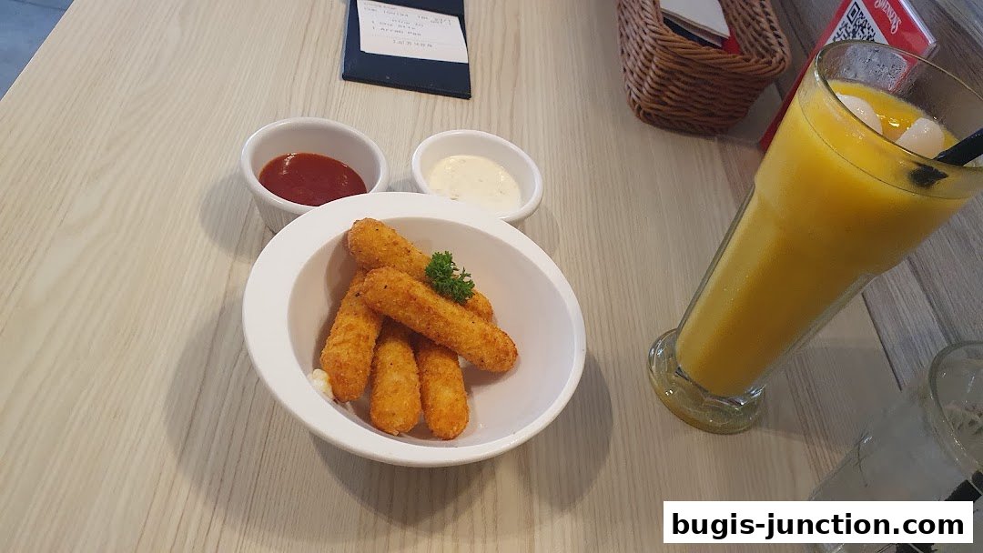 A table setting with cheese sticks, dipping sauces, and a tropical fruit smoothie.