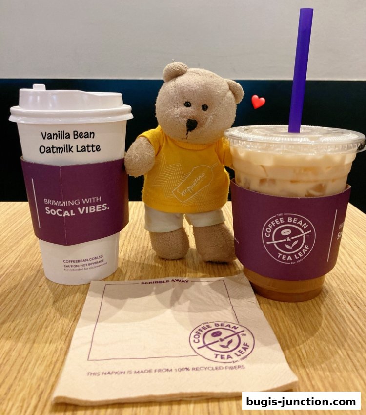 A teddy bear poses with two Coffee Bean and Tea Leaf drinks and a napkin.