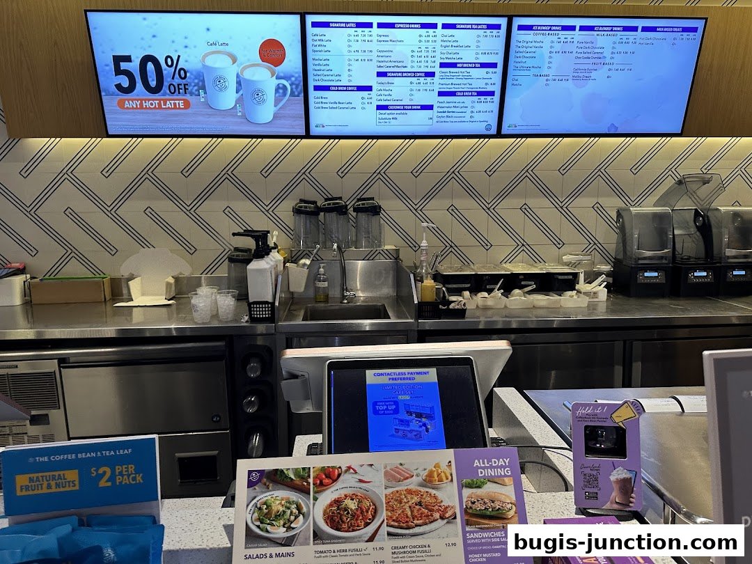 A coffee shop counter with digital menus displaying drinks, food, and promotions.