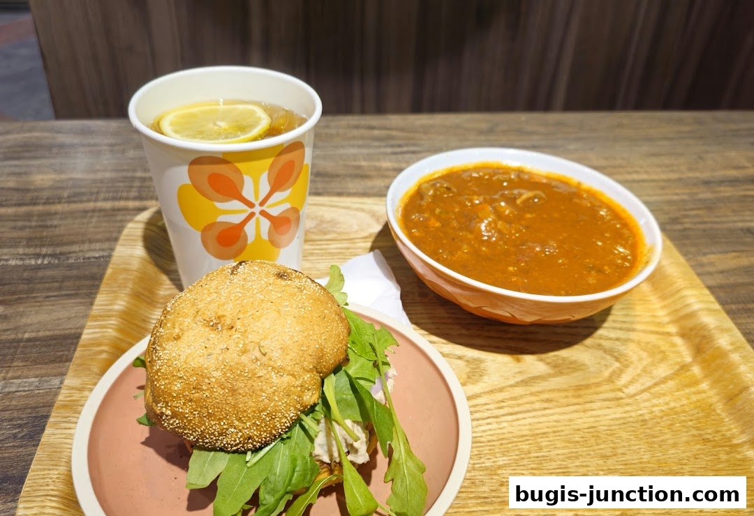 A hearty meal featuring a soup, a sandwich, and a drink with lemon.