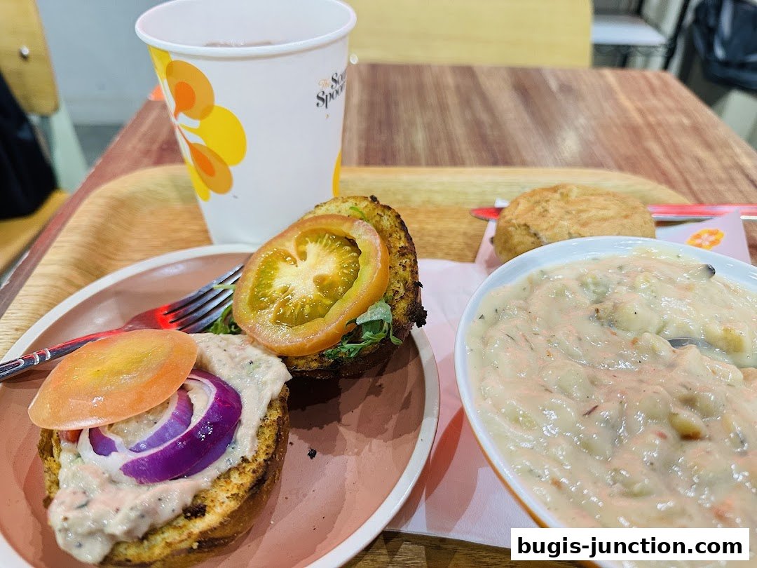 A tray with a burger, a cup, a bun, and a bowl of soup.