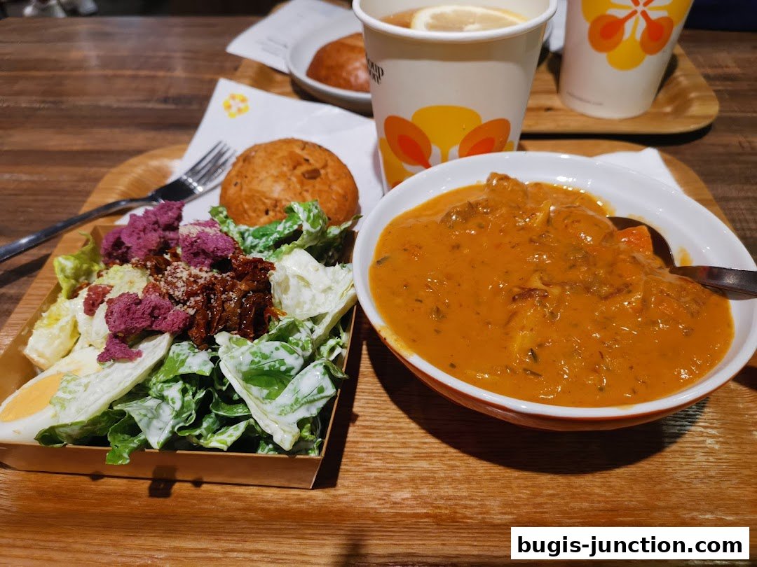 A delicious meal featuring a hearty stew, a fresh salad with egg and bread, and a cup of tea.