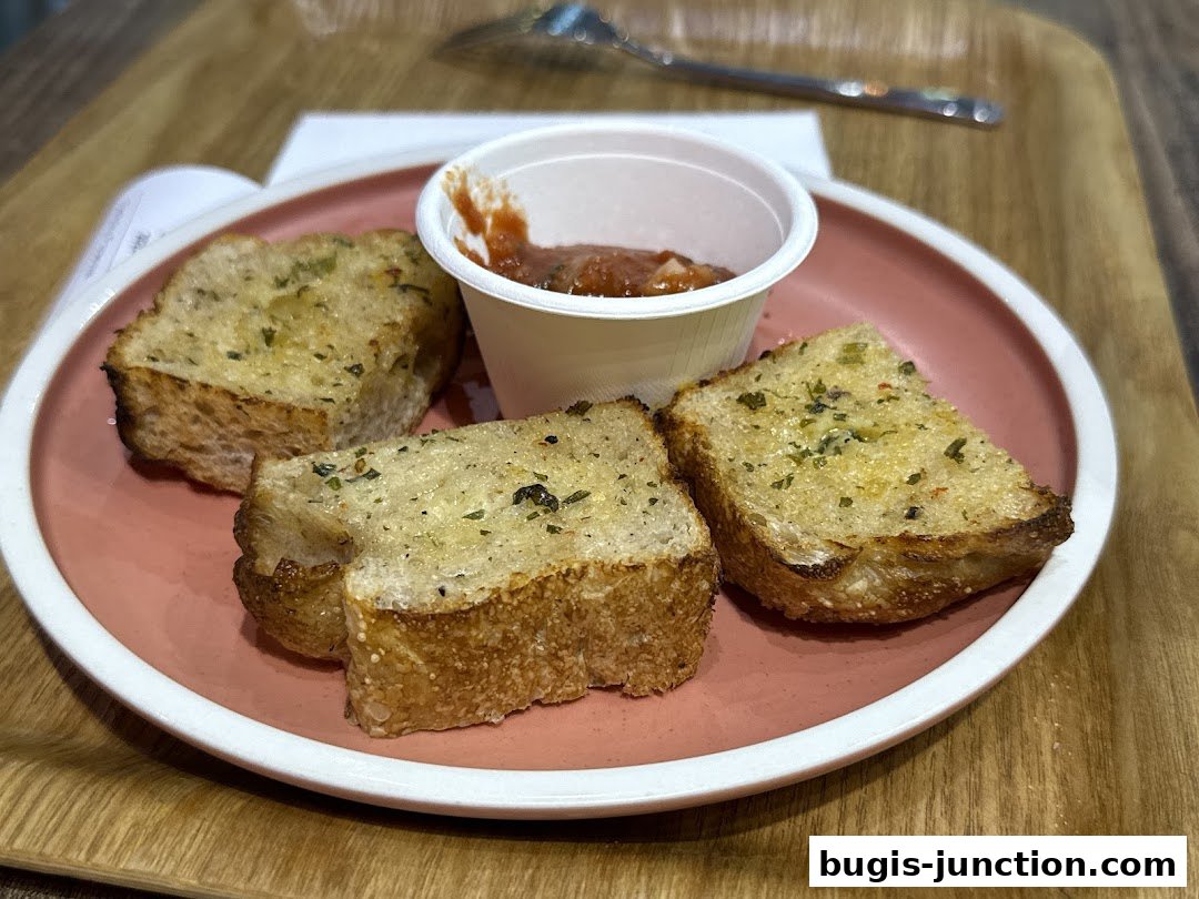 Three slices of garlic bread with herbs served with a small cup of tomato sauce.