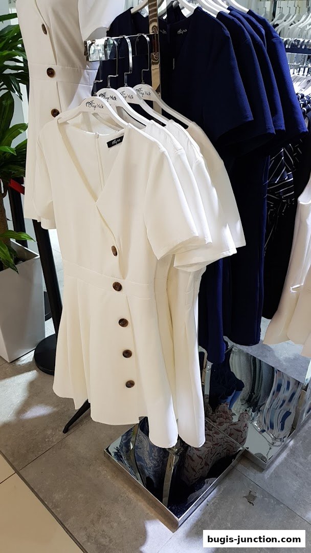 A display of white and navy dresses with button details on hangers.