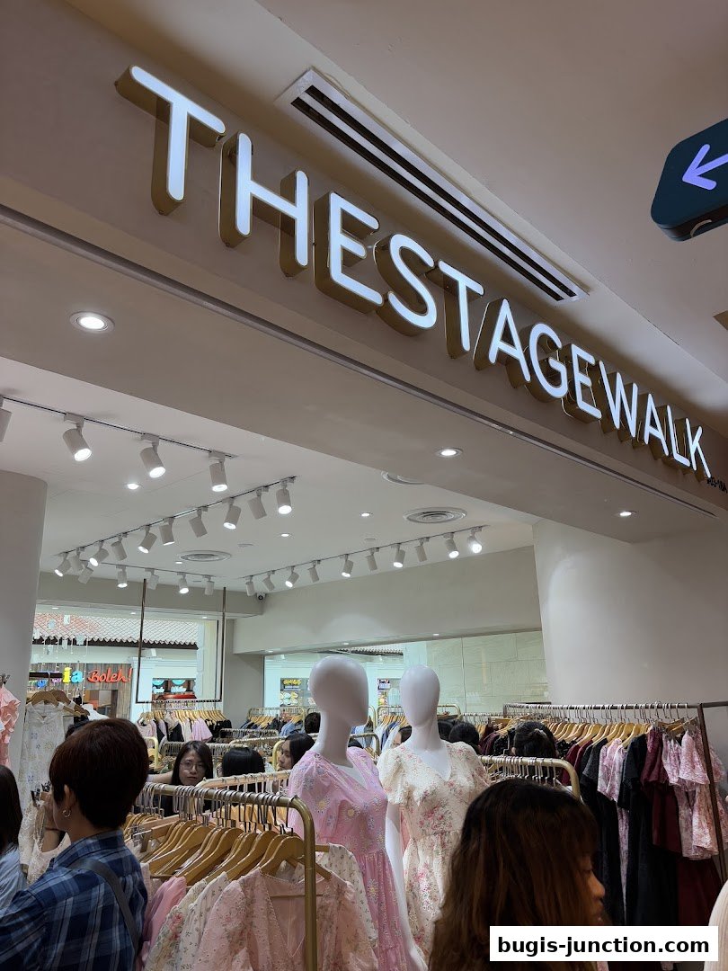 The entrance of a clothing store called "The Stage Walk" with mannequins and racks of dresses.