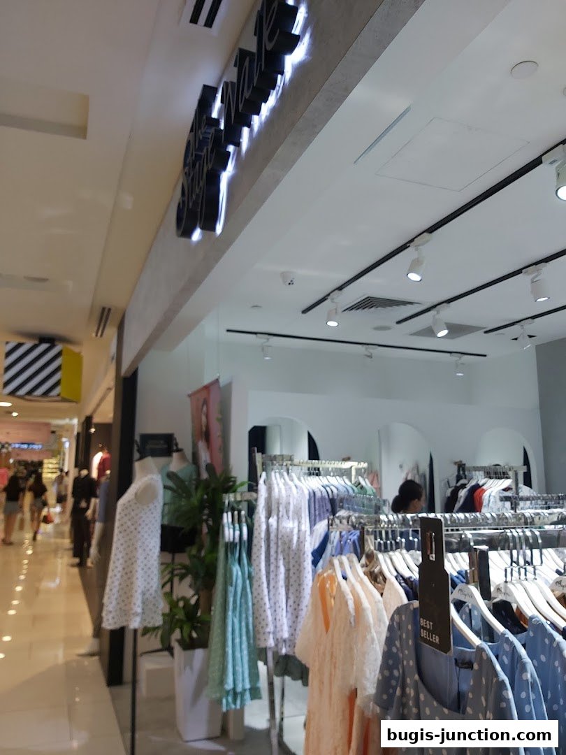 The Stage Walk clothing store entrance with mannequins and racks of dresses.