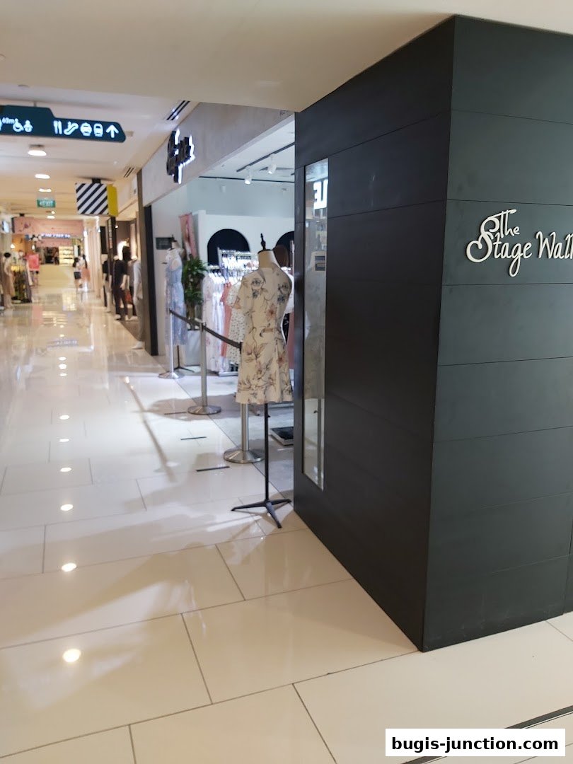 The Stage Walk shop entrance with mannequins displaying dresses and clothing racks inside.