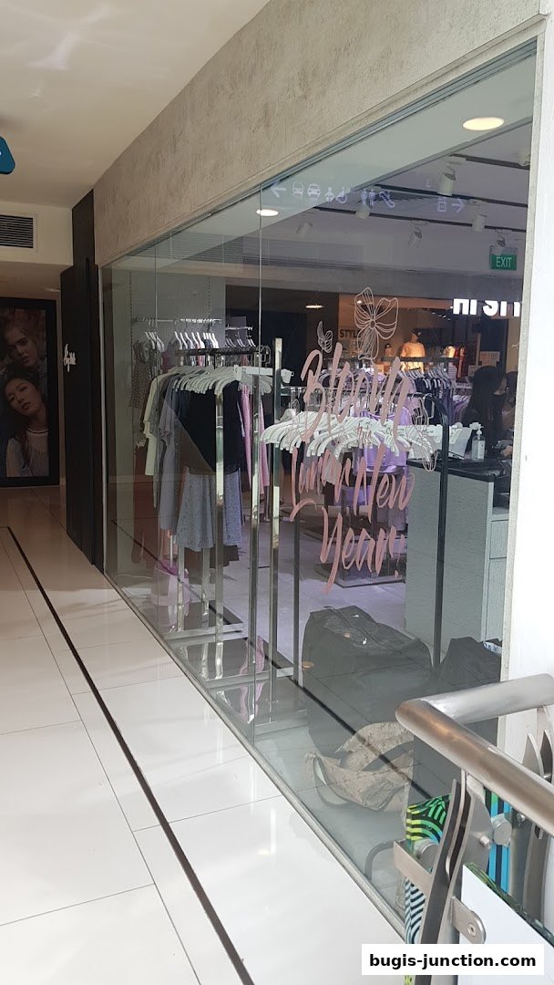 A clothing store with racks of clothes displayed behind a glass storefront.