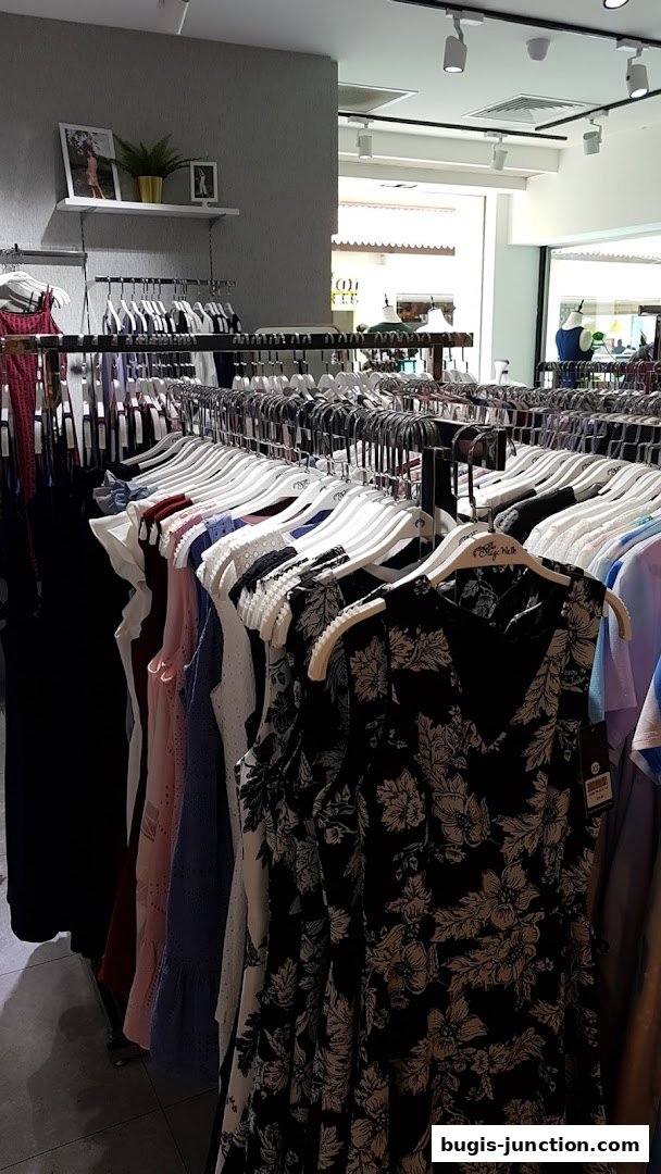 A rack of women's dresses with various patterns and colors inside a clothing store.