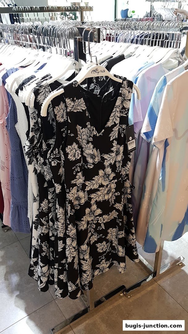 A rack of women's dresses with floral patterns and solid colors.